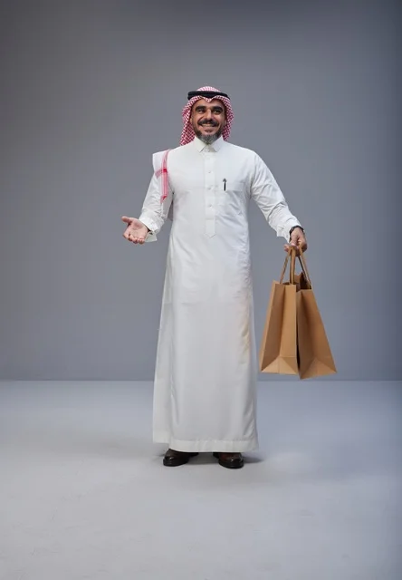 رجل سعودي بالزي التقليدي يحمل أكياس تسوق