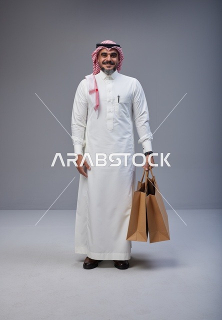 Saudi Man in Traditional Thobe Holding Shopping Bags