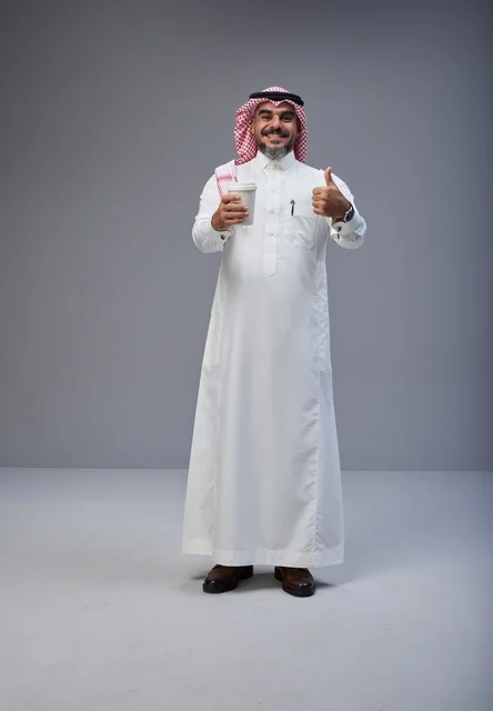 رجل سعودي بالزي التقليدي يحمل كوب قهوة