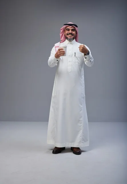 رجل سعودي بالزي التقليدي يحمل كوب قهوة