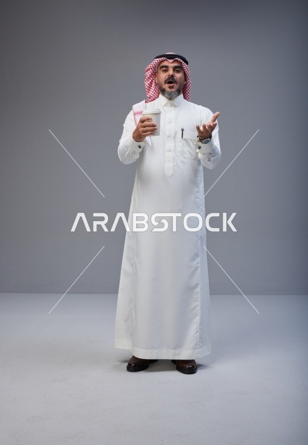 رجل سعودي بالزي التقليدي يحمل كوب قهوة