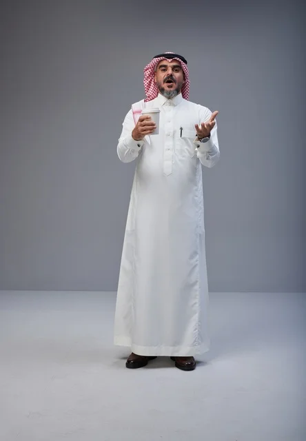 رجل سعودي بالزي التقليدي يحمل كوب قهوة