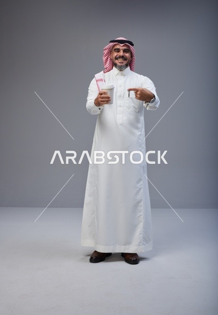 رجل سعودي بالزي التقليدي يحمل كوب قهوة