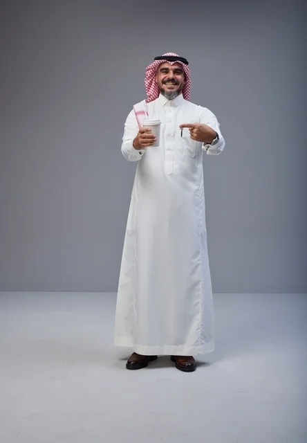 رجل سعودي بالزي التقليدي يحمل كوب قهوة