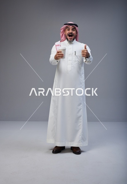 رجل سعودي بالزي التقليدي يحمل كوب قهوة