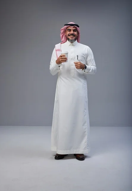 رجل سعودي بالزي التقليدي يحمل كوب قهوة