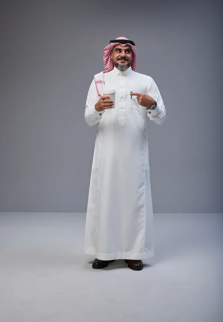 Saudi man in traditional attire holding a coffee cup