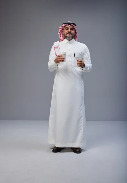 Saudi Man in Traditional Attire Holding Coffee Cup