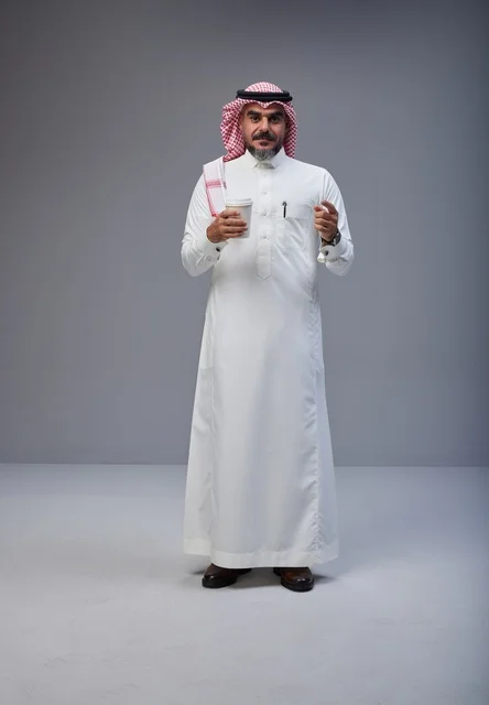 رجل سعودي بالزي التقليدي يحمل كوب قهوة