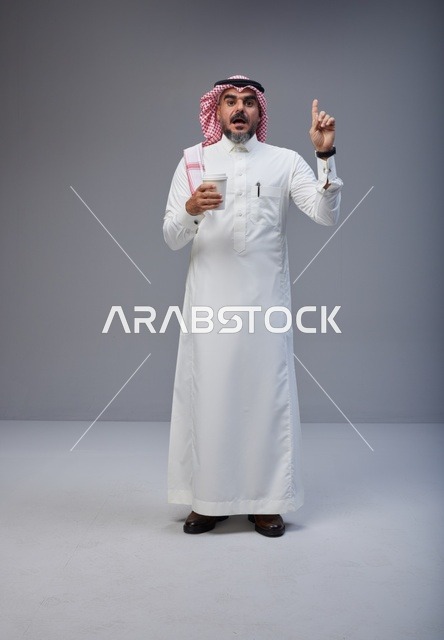 Saudi Man with Coffee Cup Pointing Up in Studio