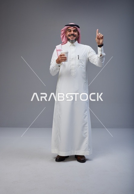 رجل سعودي بالزي التقليدي يحمل كوب قهوة
