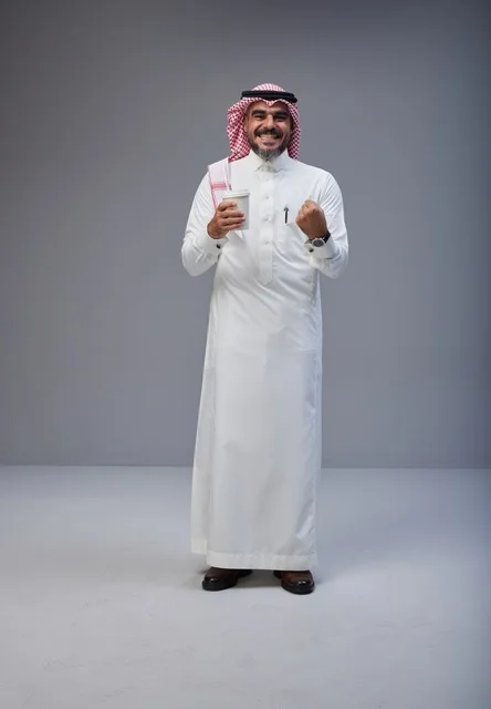 رجل سعودي بالزي التقليدي مع كوب قهوة في الاستوديو