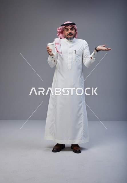 رجل سعودي حائر يحمل كوب قهوة في الاستوديو