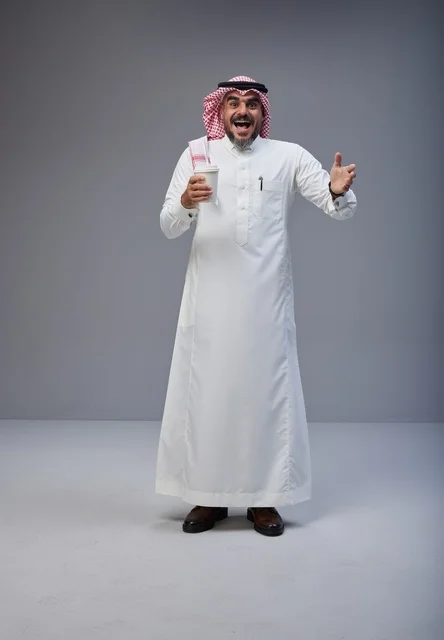 Saudi man in traditional attire holding a coffee cup