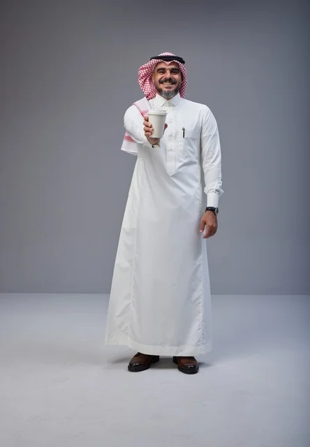 رجل سعودي بالزي التقليدي يحمل كوب قهوة