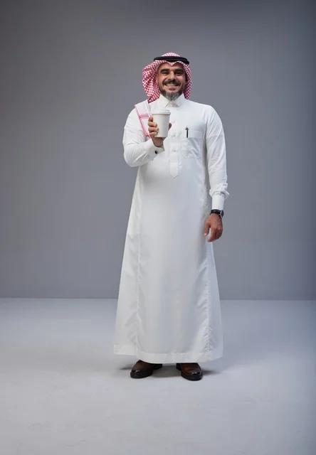 رجل سعودي بالزي التقليدي يحمل كوب قهوة