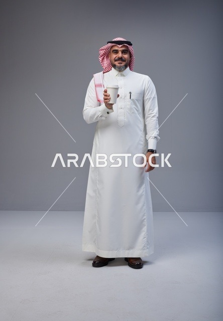 رجل سعودي بالزي التقليدي يحمل كوب قهوة في الاستوديو