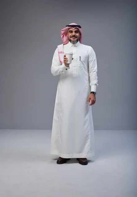 رجل سعودي بالزي التقليدي يحمل كوب قهوة في الاستوديو