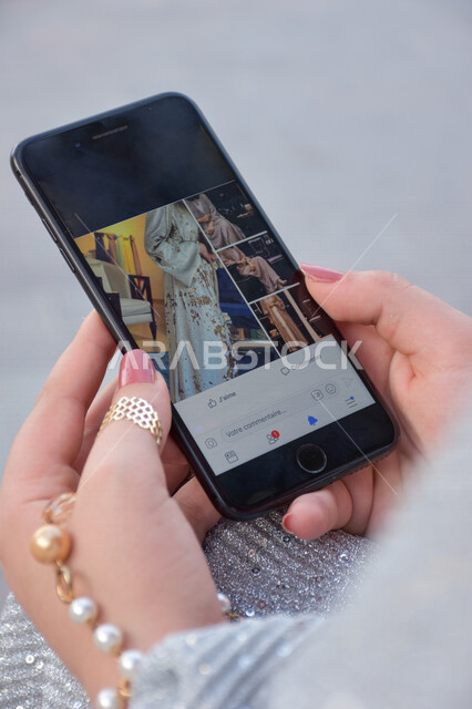 صورة لامرأة عربية خليجية تستخدم الهاتف المحمول في دبي، تصفح المواقع الالكترونية ، التسوق عبر الانترنت، البيع والشراء الالكتروني ، مشاركات واعجابات ، الأزياء، العبايات المعاصرة