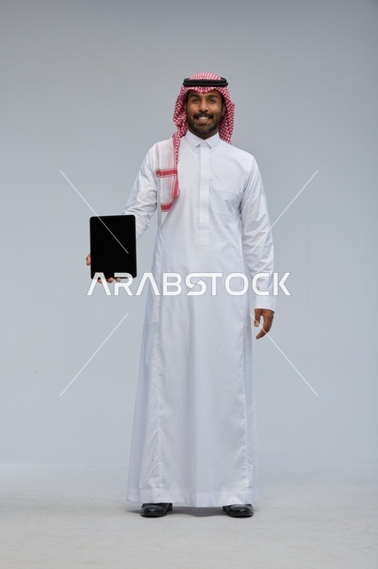 Smiling Saudi Man Holding Digital Tablet in Studio Setting