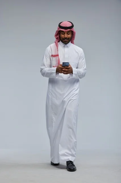 رجل سعودي بالزي التقليدي يستخدم الهاتف الذكي