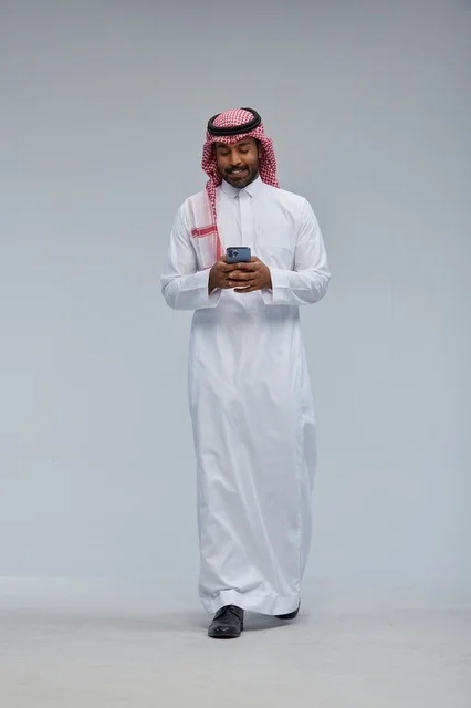 Saudi Man in Traditional Dress Using Smartphone Studio