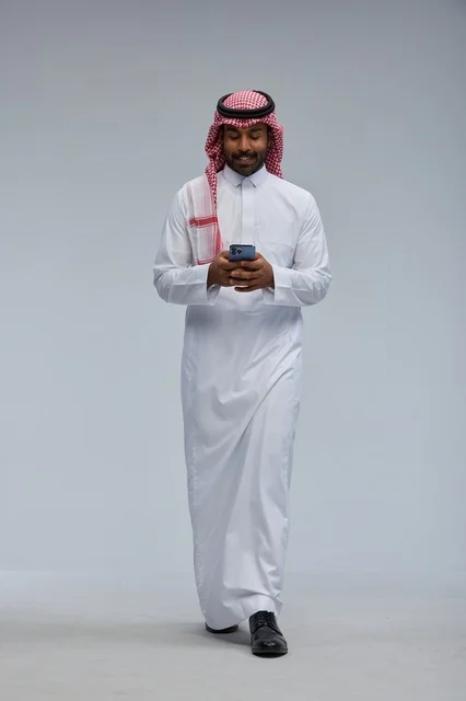 Saudi Man in Traditional Thobe Using Smartphone