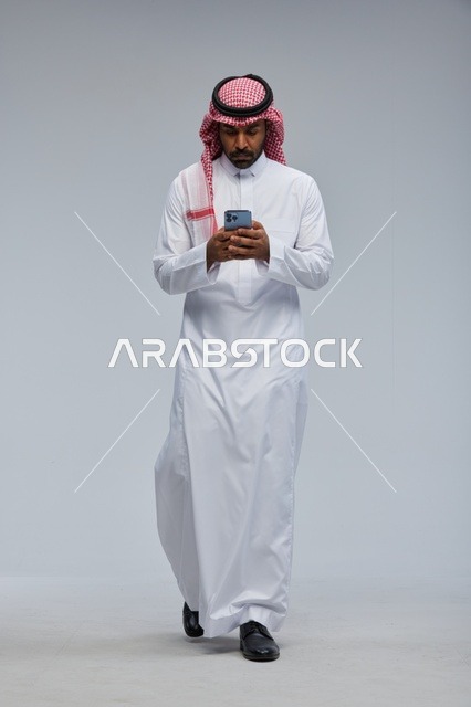 Saudi Man in Traditional Thobe Using Smartphone