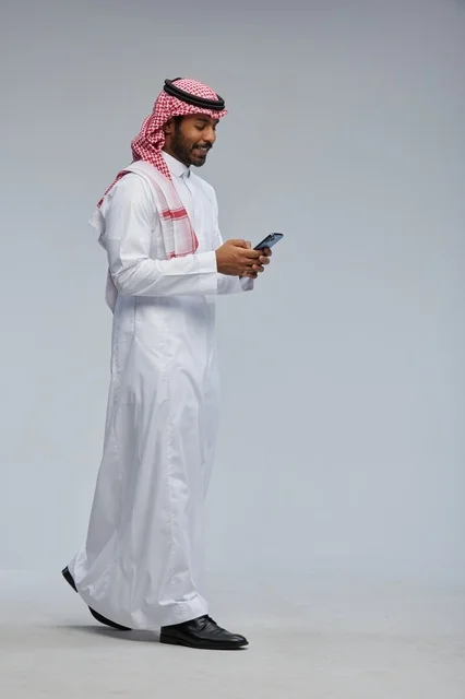 Saudi Man in Traditional Dress Using Smartphone