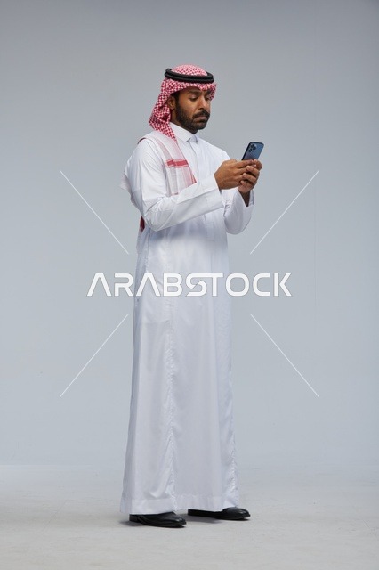 Saudi Man in Traditional Thobe Using Smartphone