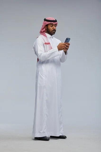 Saudi Man in Traditional Thobe Using Smartphone