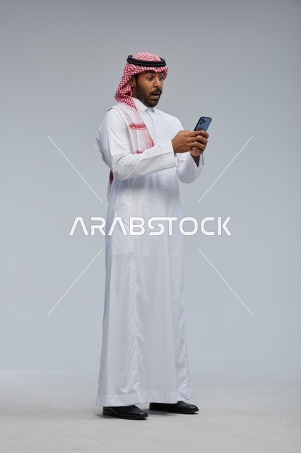 Surprised Saudi Man with Smartphone in Traditional Dress