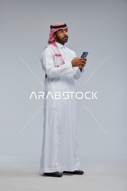 Saudi Man Using Smartphone in Traditional Dress Studio Shot