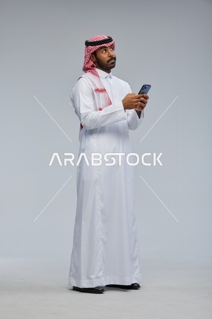 Saudi Man in Traditional Thobe Using Smartphone