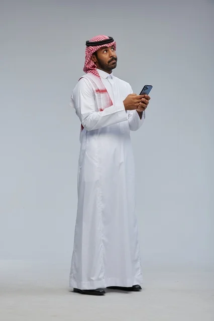 رجل سعودي بالزي التقليدي يستخدم الهاتف الذكي
