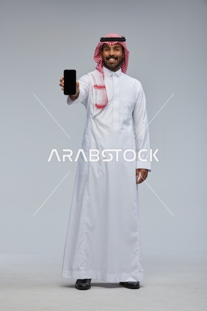 رجل سعودي يحمل هاتف ذكي في الاستوديو