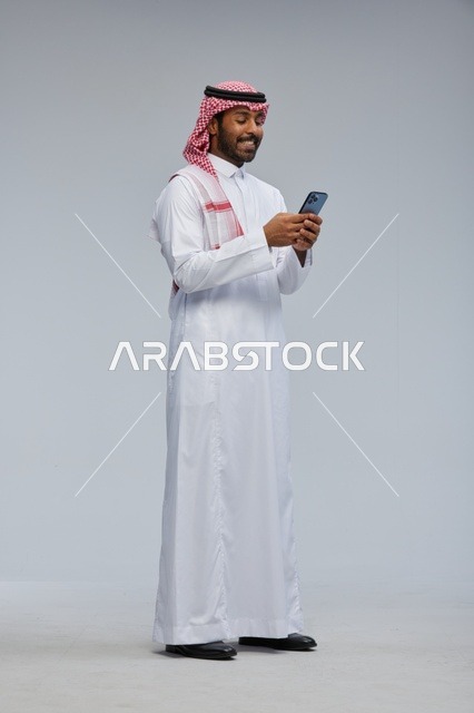 Saudi Man in Traditional Thobe Using Smartphone