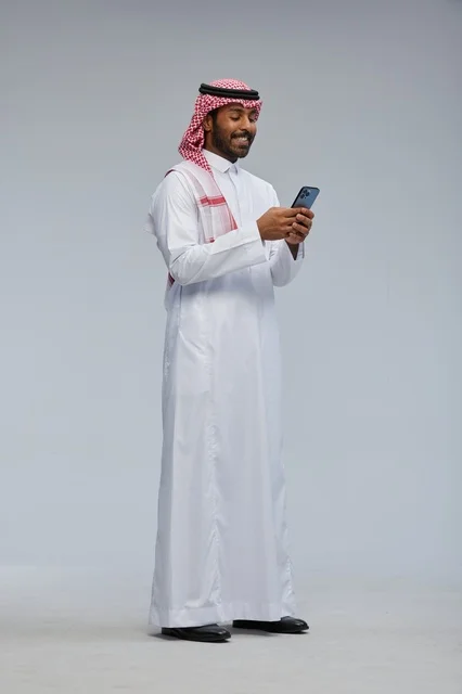 Saudi Man in Traditional Thobe Using Smartphone