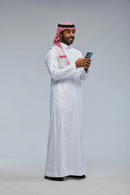 رجل سعودي بالزي التقليدي يستخدم الهاتف الذكي