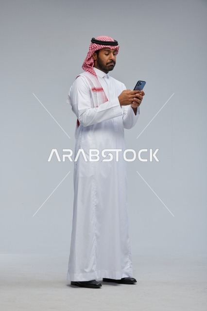 Saudi Man in Traditional Thobe Using Smartphone