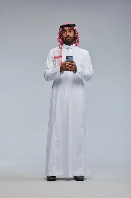 Saudi Man in Traditional Dress Using Smartphone