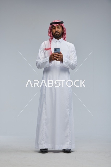 رجل سعودي بالزي التقليدي يستخدم الهاتف الذكي