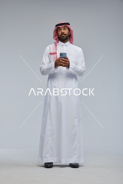 رجل سعودي بالزي التقليدي يستخدم هاتف ذكي