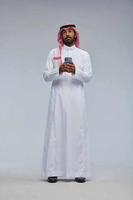 رجل سعودي بالزي التقليدي يستخدم هاتف ذكي
