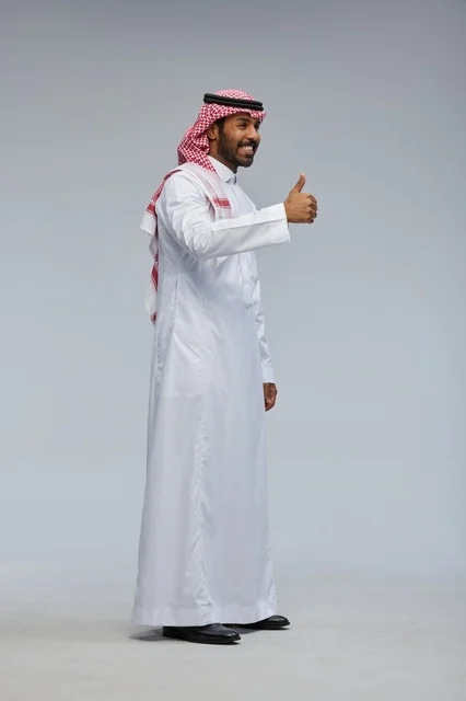 رجل سعودي بالزي التقليدي يرفع إبهامه علامة النجاح