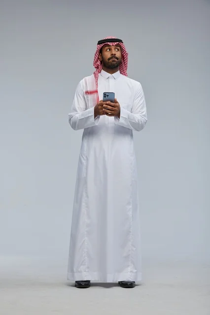 رجل سعودي بالزي التقليدي يستخدم هاتف ذكي في استوديو