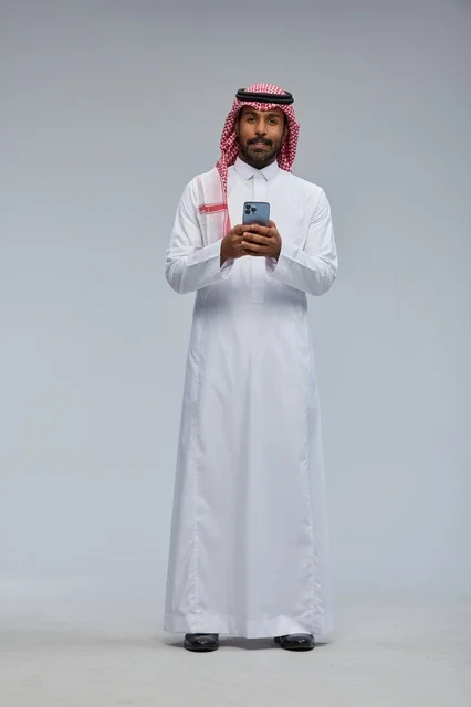 رجل سعودي بالزي التقليدي يستخدم الهاتف الذكي