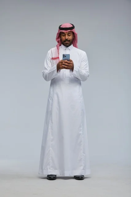 رجل سعودي بالزي التقليدي يستخدم الهاتف الذكي