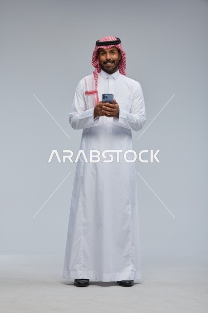 رجل سعودي بالزي التقليدي يستخدم الهاتف الذكي