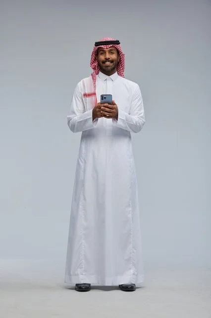Saudi Man in Traditional Dress Using Smartphone Studio Portrait